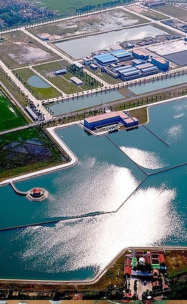 Aerial view of a large water treatment plant with multiple reservoirs, basins, and surrounding green fields.