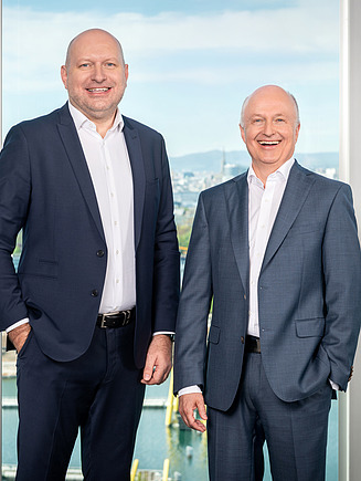 2 Manager hinter einem malerischen Blick auf Wien, Donau 