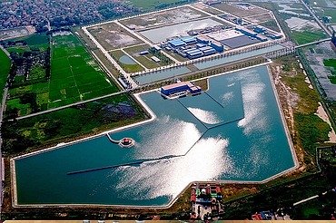 Aerial view of a large water treatment plant with multiple reservoirs, basins, and surrounding green fields.