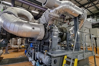 An industrial energy plant with large insulated pipes and machinery, designed for efficient energy generation and heat recovery.