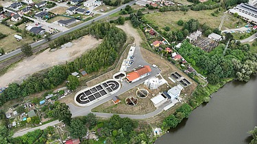 Luftaufnahme der Kläranlage in Týnec nad Sázavou mit modernen Aufbereitungsanlagen, Prozessbehältern und dem umliegenden Stadtgebiet entlang des Flussufers.