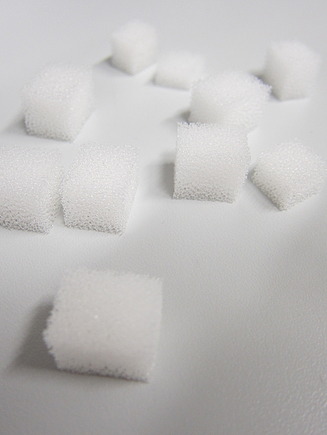 Several small white LINPOR cubes made of porous material arranged on a smooth surface. The cubes have a sponge-like texture and are evenly cut into uniform shapes.