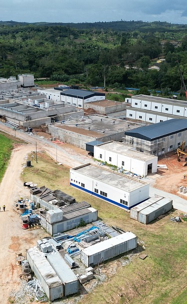 Aerial view of a large water treatment plant under construction, surrounded by green hills and open land.