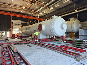 Präzise Positionierung von Wärmetauscherbehältern auf einem hydraulischen Schienensystem innerhalb der Montagehalle.