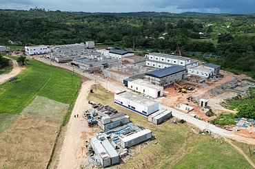 Luftaufnahme einer im Bau befindlichen großen Wasseraufbereitungsanlage, umgeben von grünen Hügeln und offenem Land.