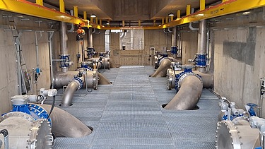 Innenansicht der Rohwasserpumpstation der Oberflächenwasseraufbereitungsanlage Xuan-Mai mit großen Wasserleitungen, Ventilen, Pumpen und Wartungsstegen.