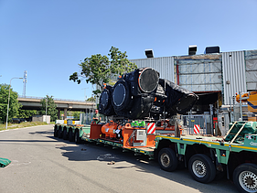 Transport of insulated industrial compressor components arriving at the site on a low-loader trailer.