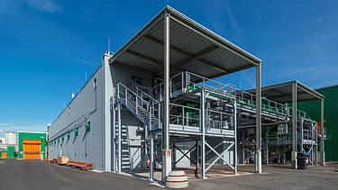 Dieses Bild zeigt eine hochmoderne industrielle Verarbeitungsanlage mit einem robusten Stahlgerüst mit erhöhten Plattformen, Treppen und integrierten Rohrleitungssystemen.