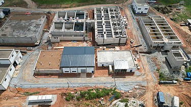 Aerial view of water treatment plant structures under construction, showing concrete tanks, filtration units, and service buildings on a cleared site.
