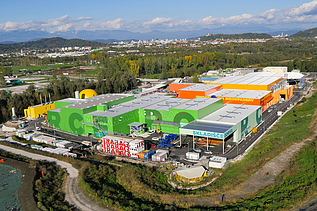 Aerial view of a large water treatment plant under construction, featuring multiple concrete structures, tanks, and surrounding green landscape.