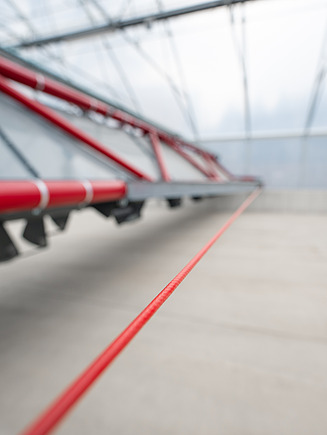 Detailaufnahme des automatischen Schlammwende- und Fördersystems in einer Solartrocknungshalle. Die Anlage lockert, wendet und transportiert den Klärschlamm während des Trocknungsprozesses und trägt so zu einer effizienten Feuchtigkeitsreduzierung bei.